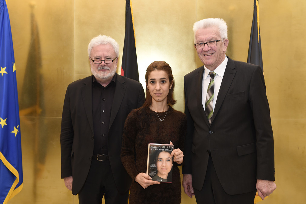 Nadia Murad (M.) übergibt ihr neues Buch „Ich bin eure Stimme“ an Ministerpräsident Winfried Kretschmann (r.) und Staatsminister Klaus-Peter Murawski (l.)