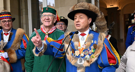 Ministerpräsident Winfried Kretschmann (zweiter von links) und Rainer Hespeler (rechts), Präsident der Narrenvereinigung Bodensee-Hegau, vor dem Neuen Schloss in Stuttgart.