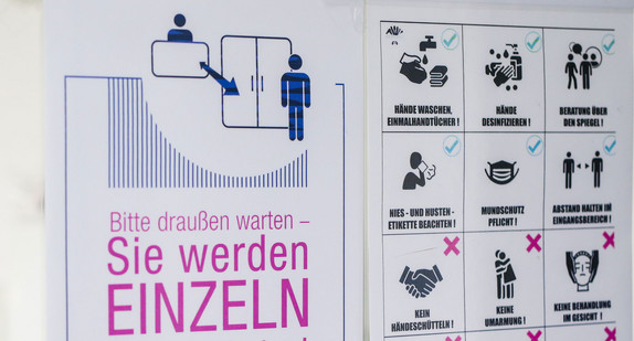 Ein Schild mit der Aufschrift „Bitte draußen warten – Sie werden einzeln hereingebeten!“ und weiteren Verhaltensvorgaben weist Kunden in einem Friseursalon über die neu geltenden Regeln im Salon aufgrund der Corona-Pandemie hin.