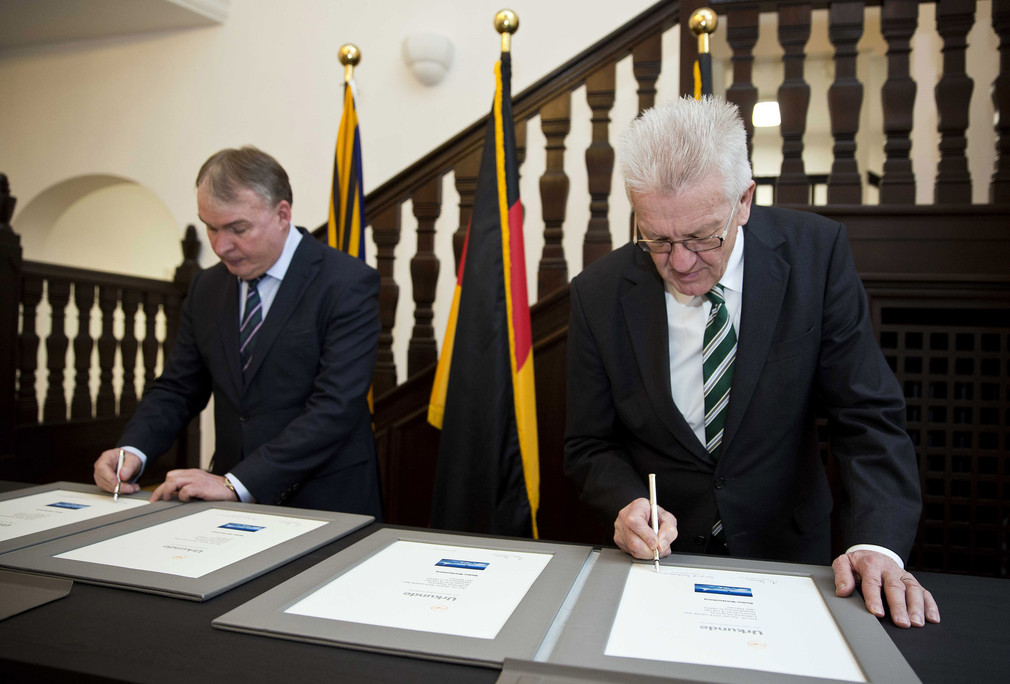 Ministerpräsident Winfried Kretschmann (r.) und Thomas Kropp (l.), Lufthansa AG, bei der Unterzeichnung der Urkunde zur Übertragung des Namens „Baden-Württemberg“ auf ein Lufthansa-Flugzeug.