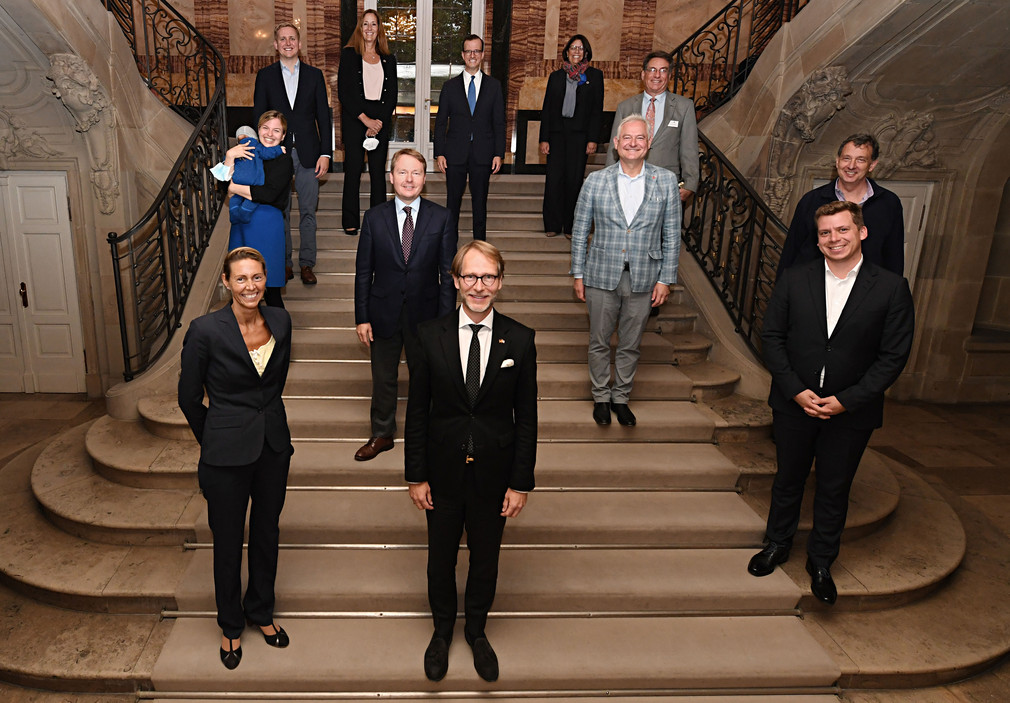 Staatsminister Dr. Florian Stegmann (vorne Mitte) steht mit der Direktorin des Aspen Institut Deutschland, Dr. Stormy-Annika Mildner (vorne links), und den Mitgliedern einer deutsch-amerikanischen Parlamentariergruppe auf einer Treppe im Neuen Schloss in Stuttgart.