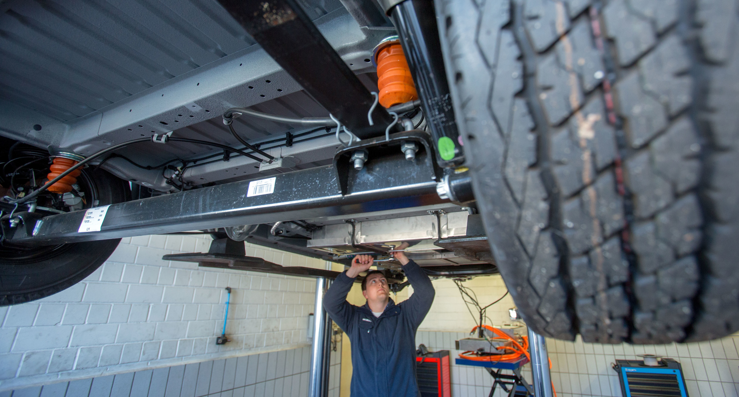 Ein Mechaniker montiert Batterieblöcke in einer Autowerkstatt. (Bild: © dpa)']